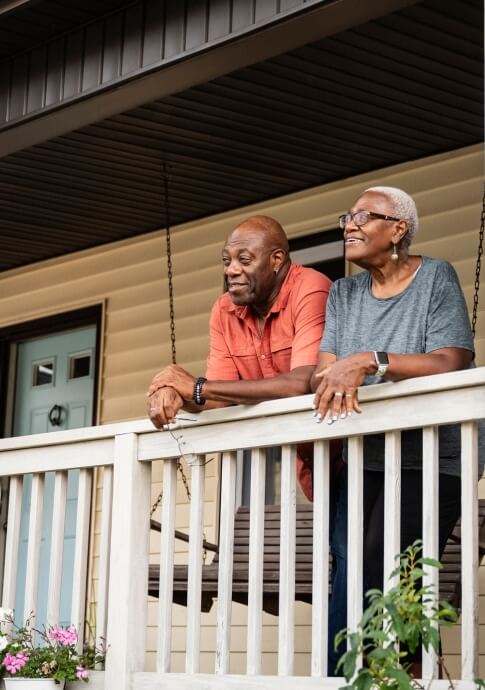 Mature couple smiling on the front porch of their home