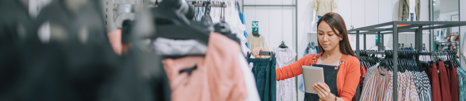 Small business owner reviewing tablet in her boutique clothing store.