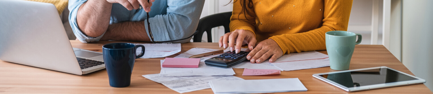 Couple working on calculator and laptop at kitchen table